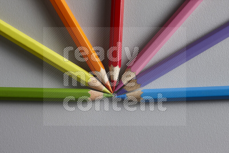 An arrangement of colored pencils in different colors on grey background