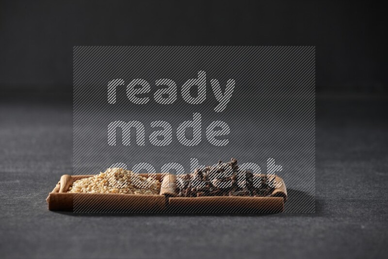 2 squares of cinnamon sticks full of sesame and cloves on black flooring