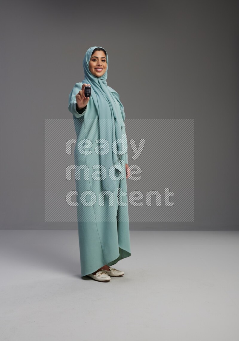 Saudi Woman wearing Abaya standing holding car key on Gray background