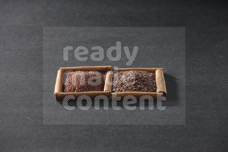 مربعان من أعواد القرفة ممتلئان بحب الرشاد وبذور الكتان علي خلفية سوداء