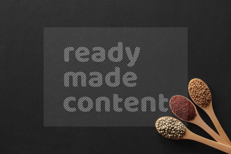 wooden spoons filled with white peppers, mustard seeds, black seeds, garden cress, cumin and flax on black flooring