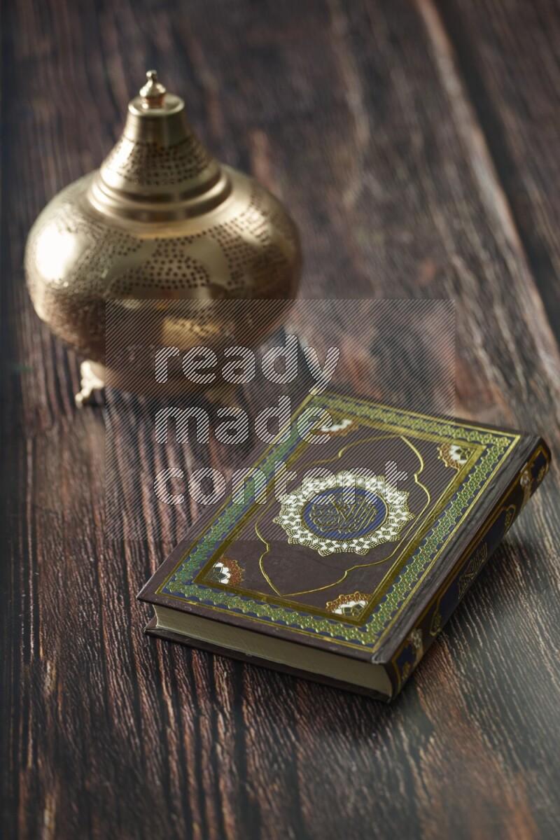 A golden lantern with different drinks, dates, nuts, prayer beads and quran on brown wooden background