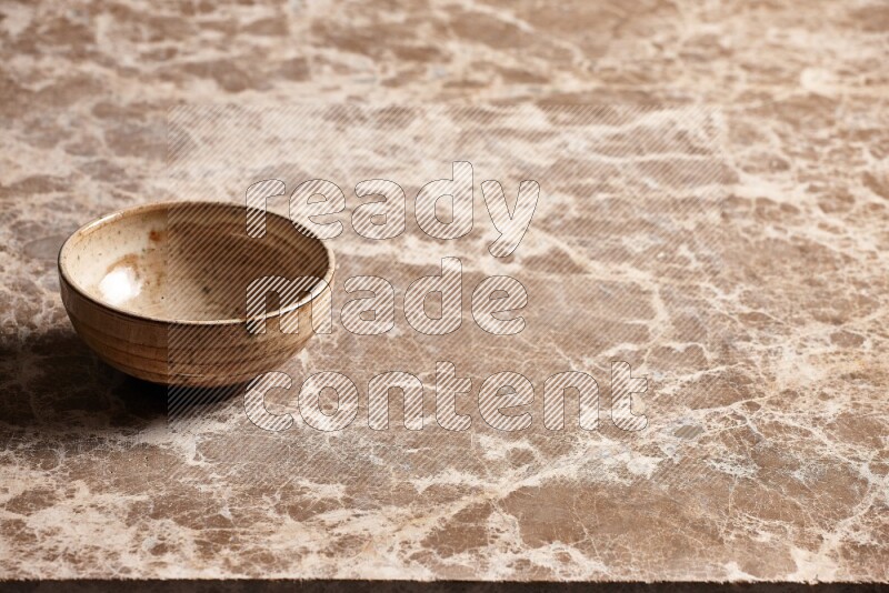 A beige pottery bowl on beige marble background
