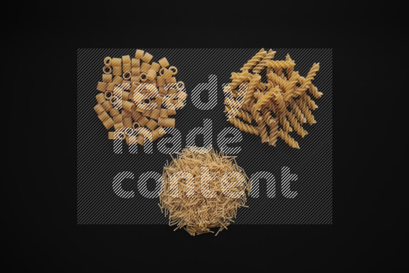 Different pasta types in bunches on black background