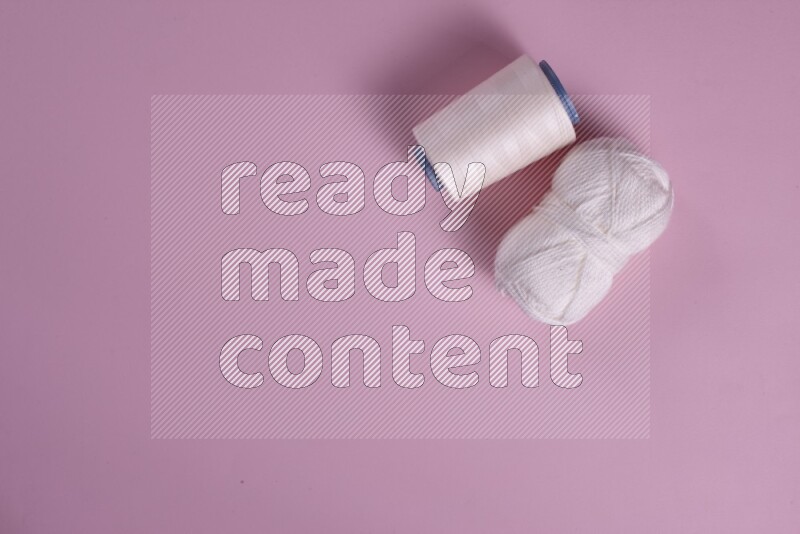 A white and pink collection of sewing and tailoring tools arranged on a pink background