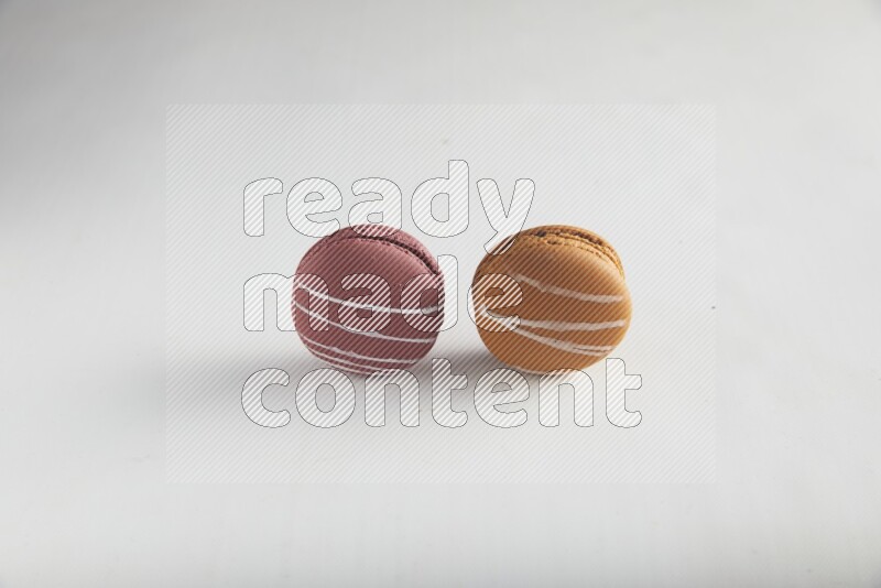 45º Shot of of two assorted Brown Irish Cream, and Red Poppy Flower macarons on white background