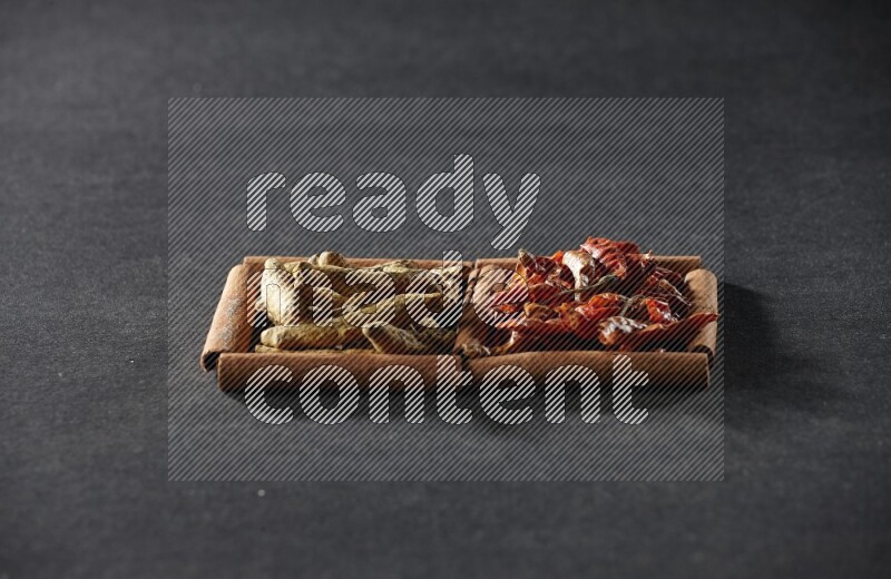 مربعان من أعواد القرفة ممتلئان بالفلفل الحار المجفف وأصابع الكركم علي خلفية سوداء