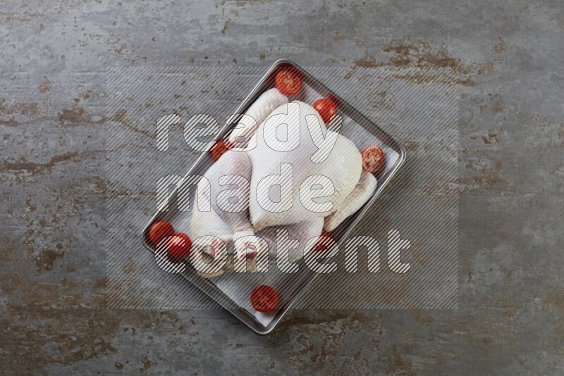 whole Raw chicken on a small oven trey direct on a rustic grey background