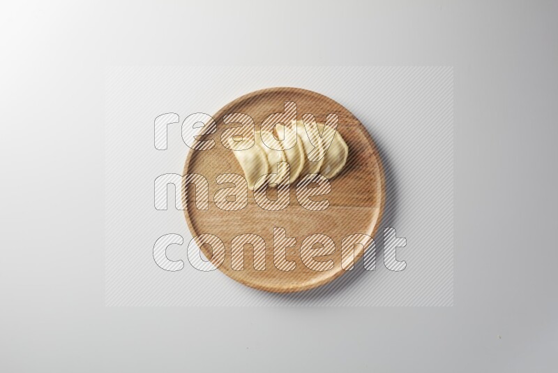 Five Sambosas on a wooden round plate on a white background