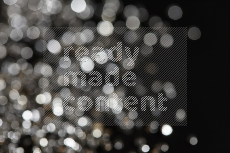 قطع زجاجية فضية لامعة متناثرة على خلفية سوداء