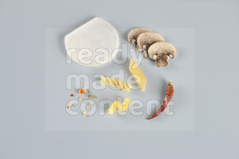 Raw pasta with different ingredients such as cherry tomatoes, garlic, onions, red chilis, black pepper, white pepper, bay laurel leaves, rosemary, cardamom and mushrooms on light blue background
