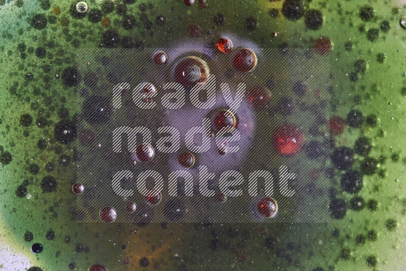 Close-ups of abstract red, green and blue watercolor drops on oil Surface on green background