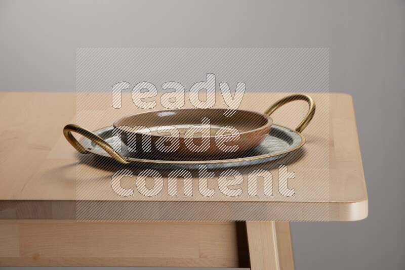 multicolored plate placed on a rounded stainless steel tray with golden handels on the edge of wooden table