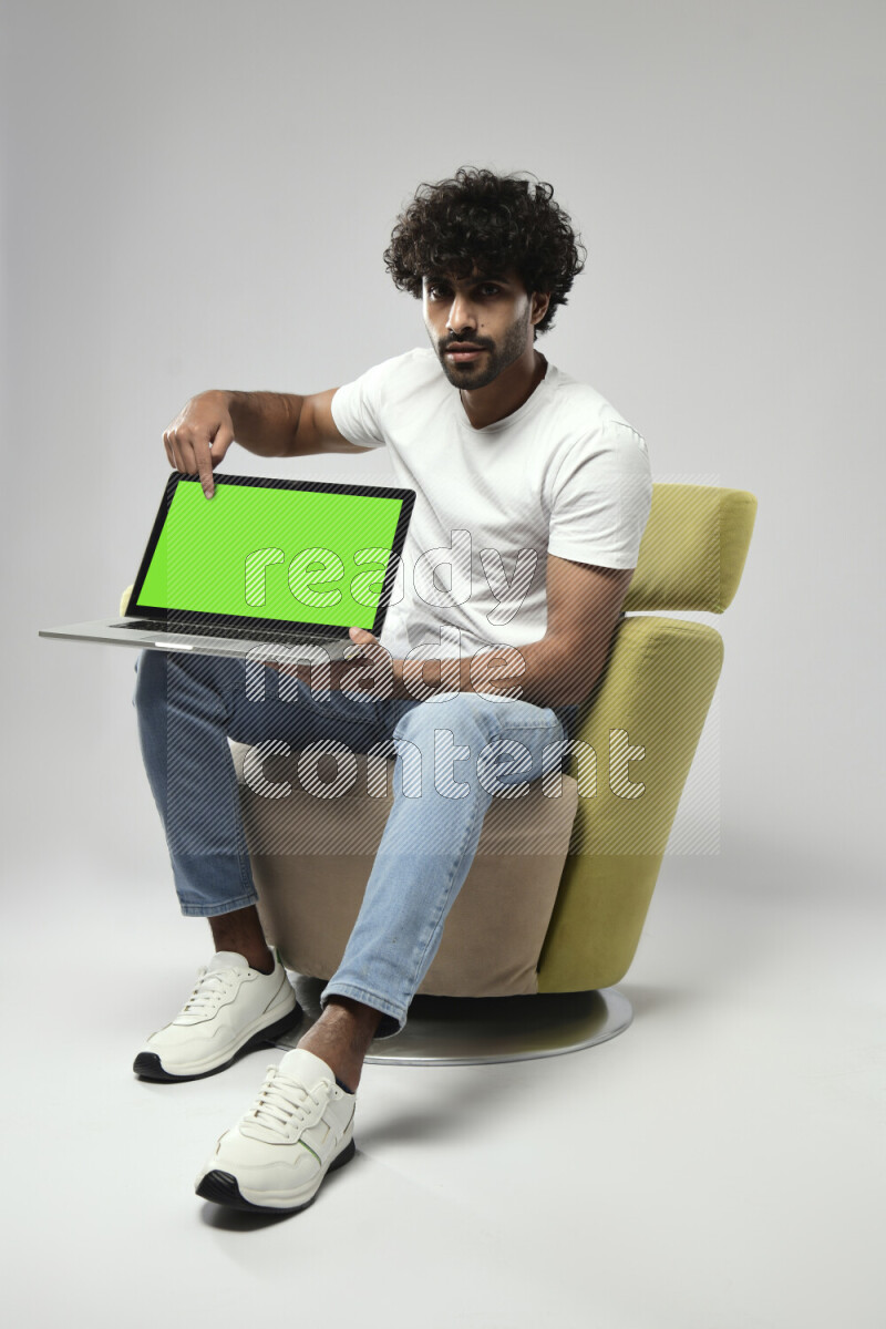 A man wearing casual sitting on a chair showing a laptop screen on white background