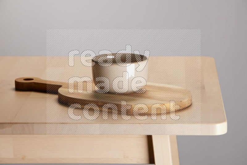 multi colored bowl placed on a  wooden oval cutting board on the edge of wooden table