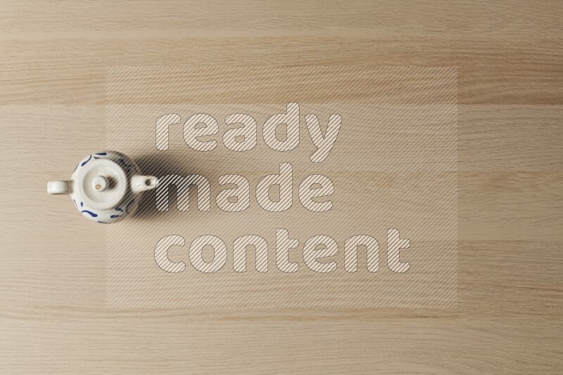 إبريق شاي فخاري على خلفية خشبية فاتحة