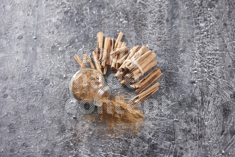 قرفة في وعاء زجاجي مقلوب مع أعواد القرفة المربوطة علي خلفية سوداء