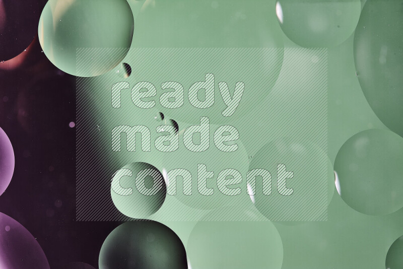 لقطات مقربة لفقاعات من الزيت على سطح الماء باللون الأخضر والوردي