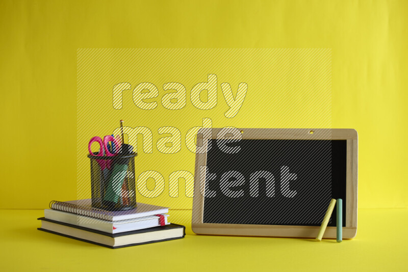 A blackboard with different school supplies on yellow background