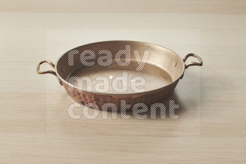 A small copper pan on light wooden background