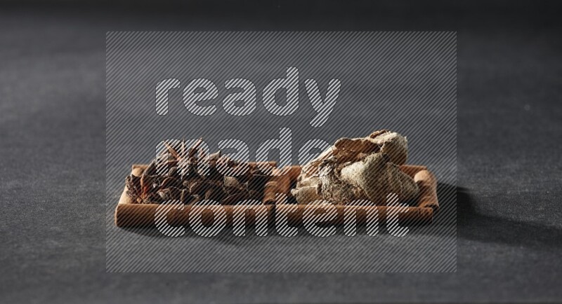 مربعان من أعواد القرفة ممتلئان باليانسون النجمي والزنجبيل المجفف علي خلفية سوداء