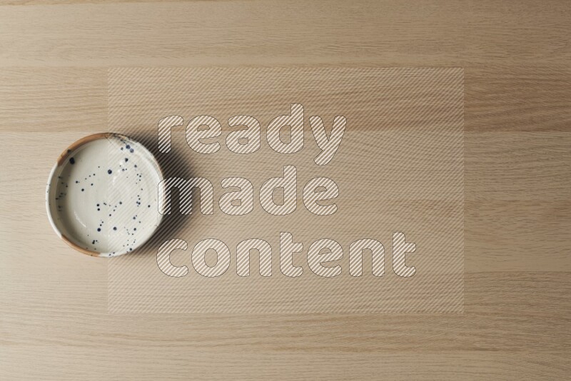 A multicolored pottery bowl on light wooden background