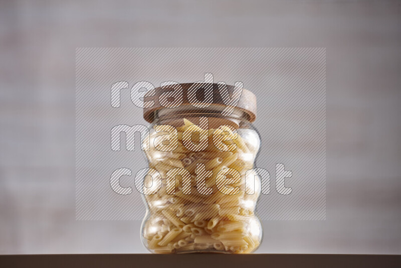 Raw pasta in glass jars on beige background