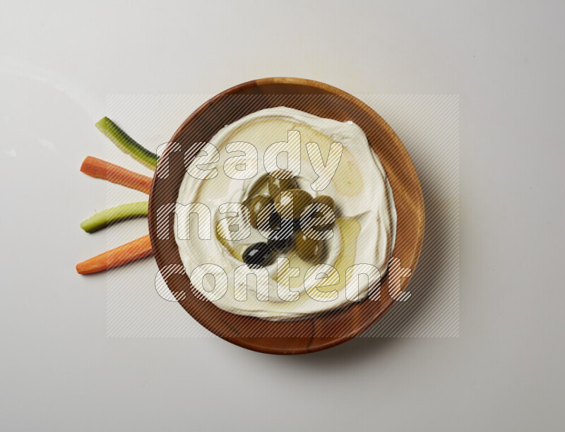 Lebnah garnished with whole olives in a wooden plate on a white background