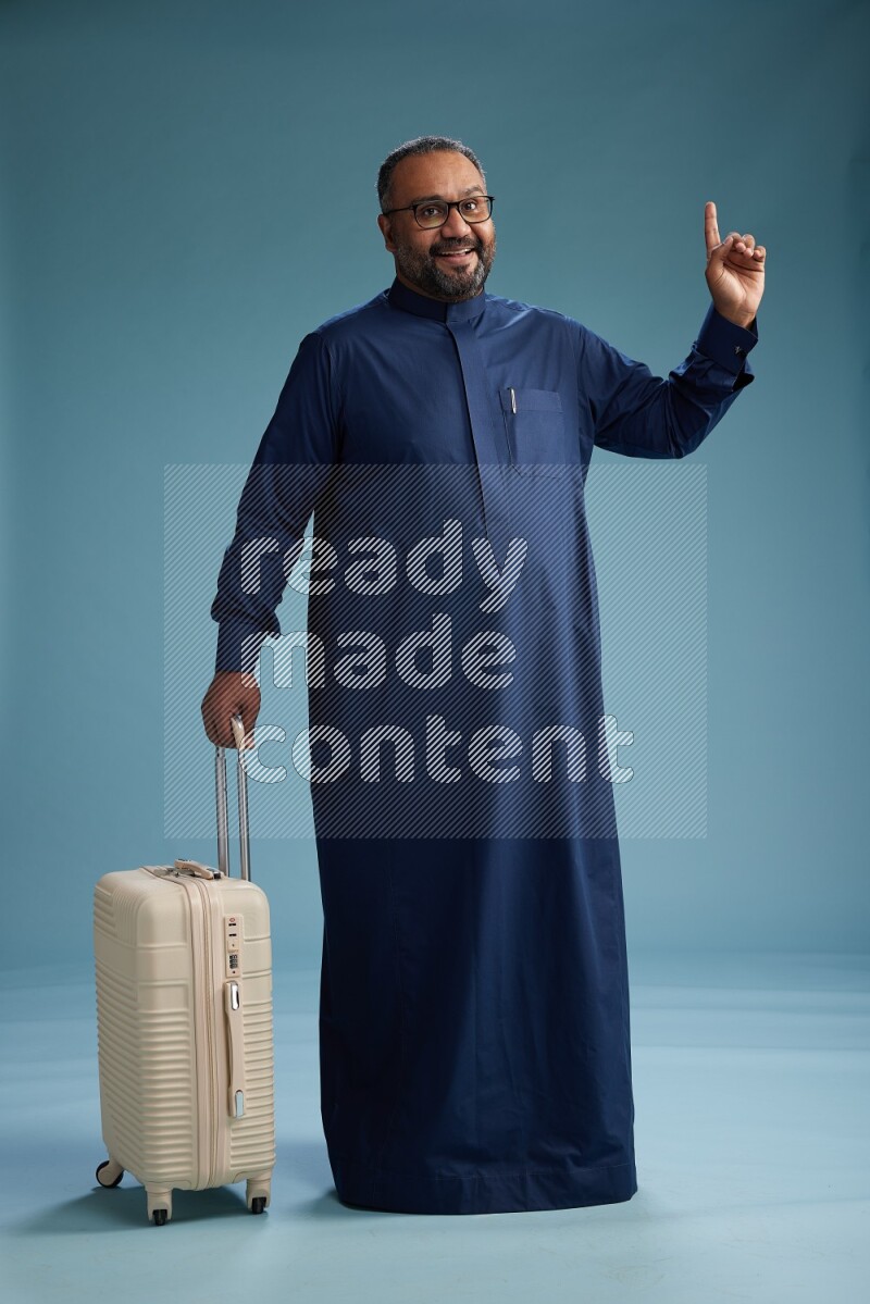 Saudi Man without shimag Standing pulling travel bag on blue background