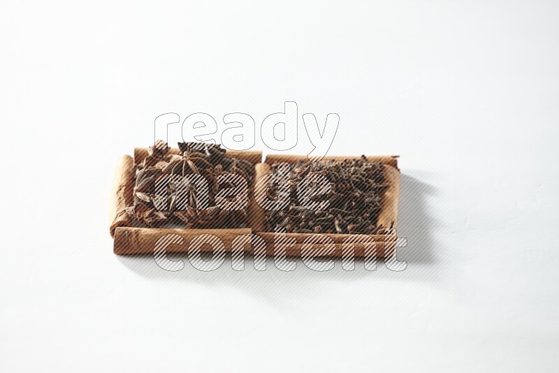 2 squares of cinnamon sticks full of cloves and star anise on white flooring