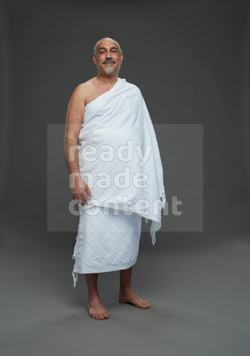 A man wearing Ehram Standing Interacting with the camera on gray background