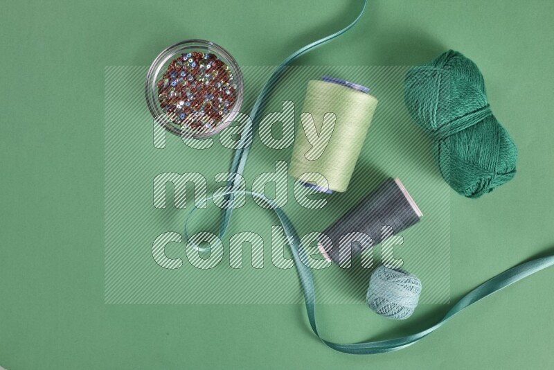 A green collection of sewing and tailoring tools arranged on a green background