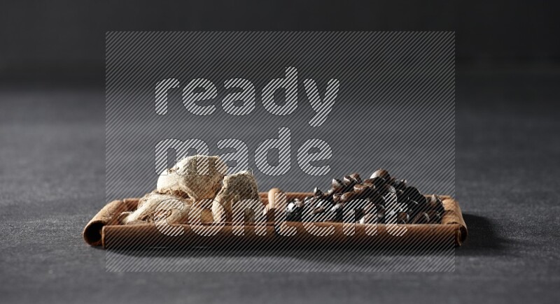 2 squares of cinnamon sticks full of coffee beans and ginger on black flooring