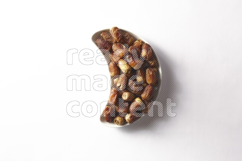 تمر في صحن فخار هلالي على خلفية بيضاء