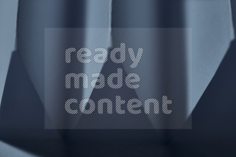 صورة مجردة مقربة تظهر طيات ورقية هندسية حادة بتدرجات اللون الأزرق