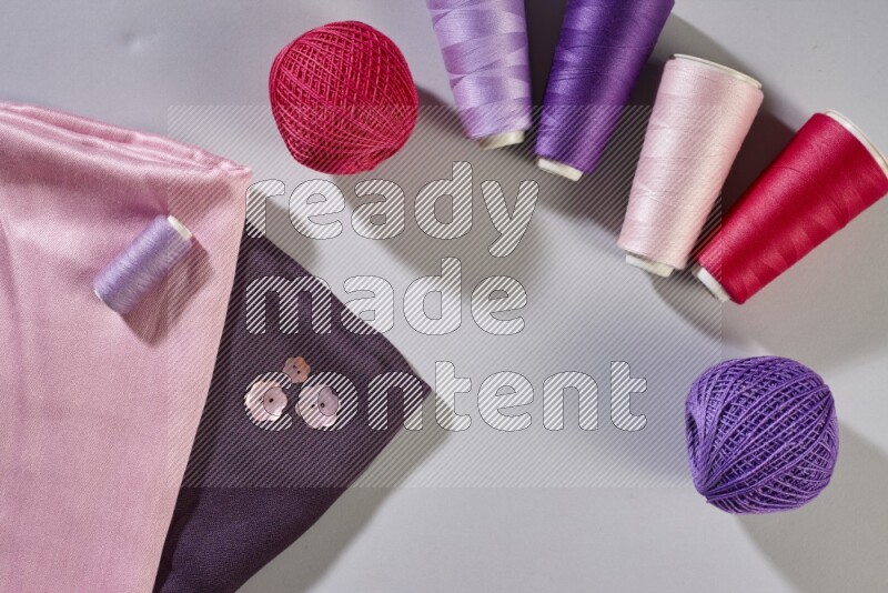 Multicolored fabrics with sewing supplies on grey background