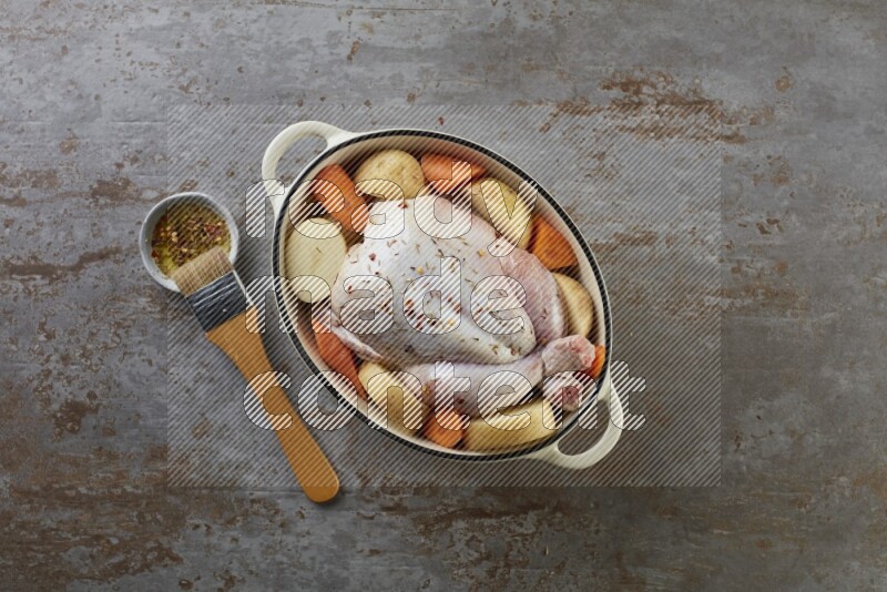 whole raw chicken on in a white ceramic pot direct on a rustic grey background