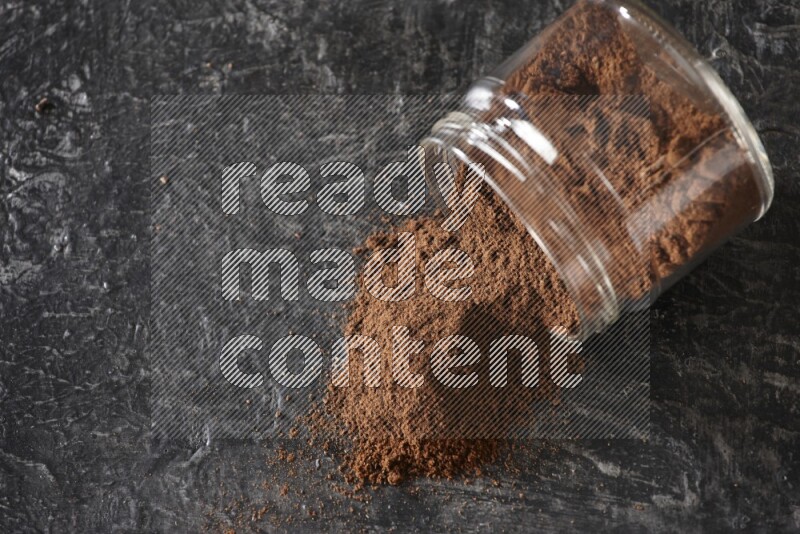 وعاء زجاجي مقلوب ممتلئ ببودرة القرنفل على أرضية سوداء