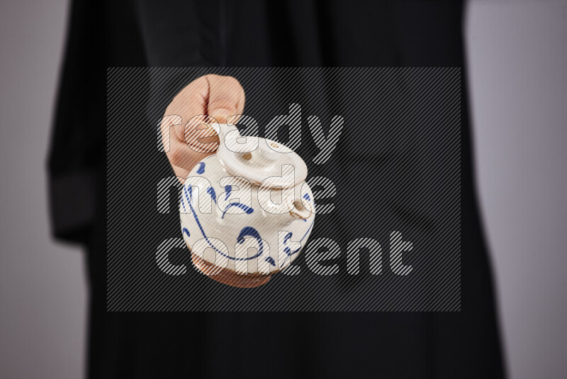 امرأة ترتدي عباءة سوداء تحمل أدوات فخارية مختلفة في أوضاع متعددة