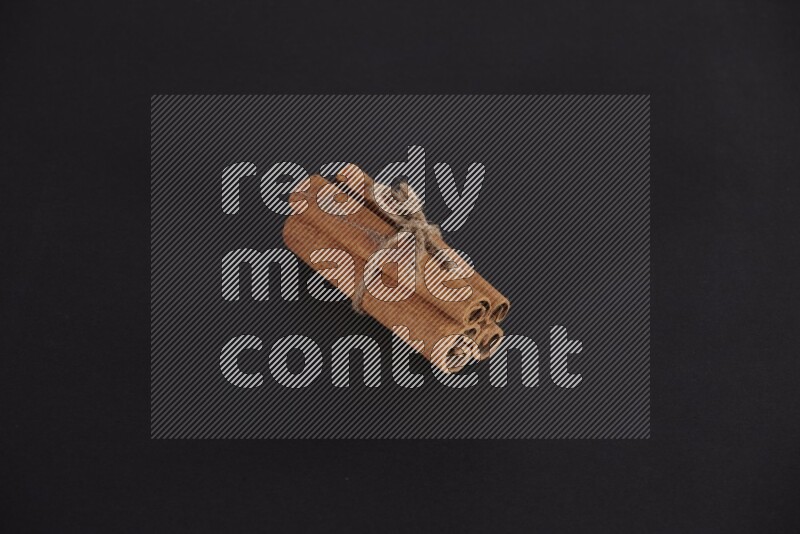 4 أعواد من القرفة مربوطة علي خلفية سوداء