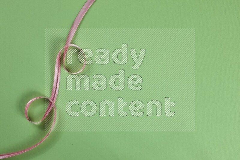 A pink collection of sewing and tailoring tools arranged on a green background