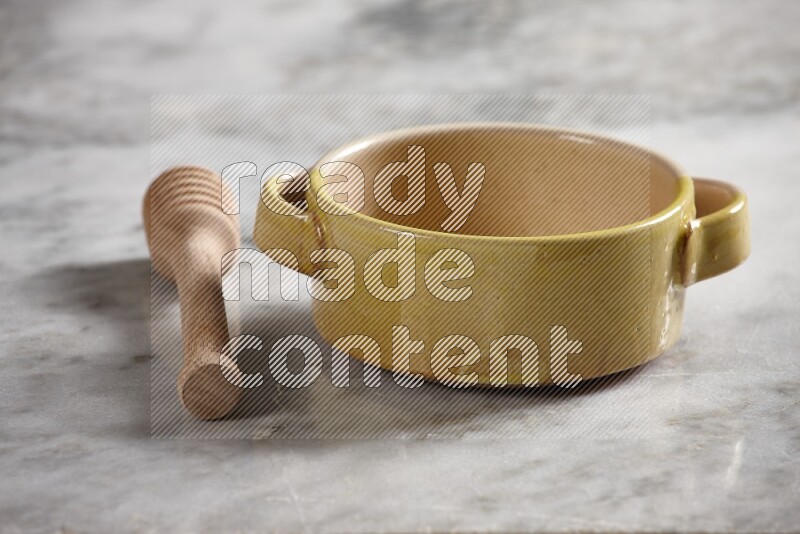 Multicolored pottery bowl with wooden honey dipper on the side on grey marble background