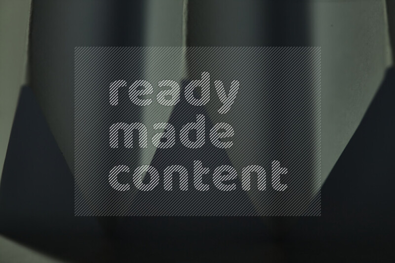 صورة مجردة مقربة تظهر طيات ورقية هندسية حادة بتدرجات اللون الأخضر