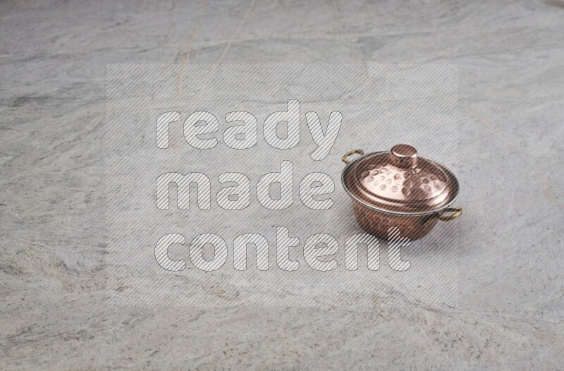A small copper pot on grey marble background