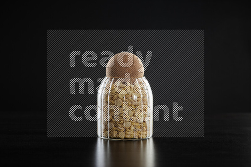 Crushed beans in a glass jar on black background