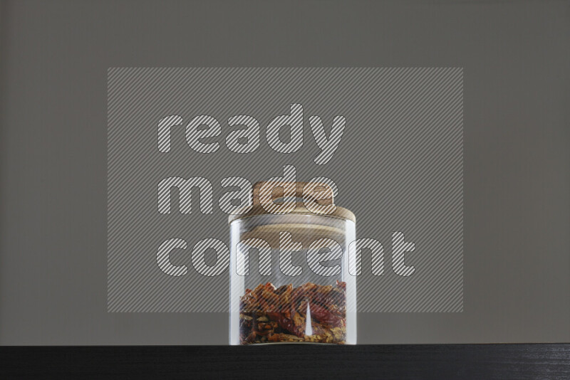 Chili pepper in a glass jar on black background