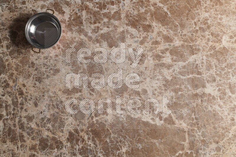 A small copper pot on beige marble background