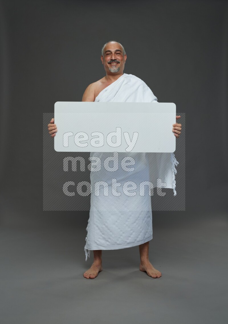 A man wearing Ehram Standing holding social media sign on gray background