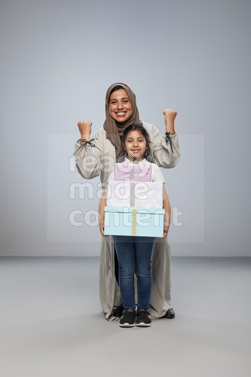 A girl giving a gift to her mother on gray background