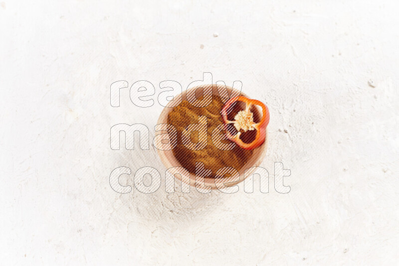 A wooden bowl full of ground paprika powder on white background